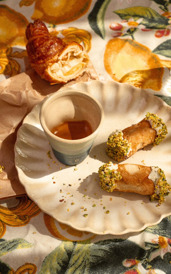 Espresso van Battito geserveerd met Italiaanse cornetto en cannoli op een tafelkleed met citroenen